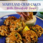 Dunking Maryland crab cakes into remoulade sauce.