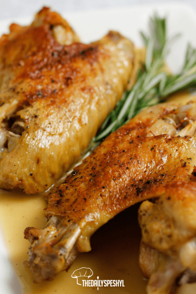 Braised Turkey Wings with Pan Gravy on a plate garnished with fresh rosemary