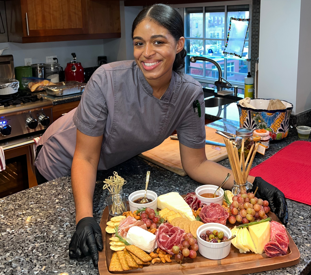 Chef Speshyl Smith smiling and posing in front of a charcuterie board she made.