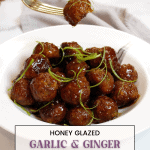Honey Glazed Garlic And Ginger Meatballs garnished with thinly sliced scallions in a white bowl. One meatball is being picked up with a gold fork.
