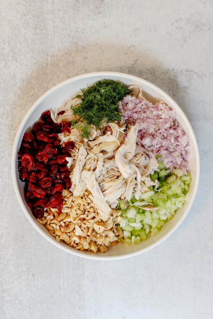 A white bowl filled with curry chicken salad ingredients.