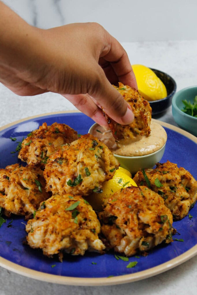 Dunking Maryland crab cakes into remoulade sauce.