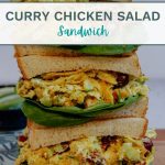 Three stacked curry chicken salad sandwiches on a cutting board.