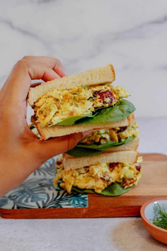 Holding a curry chicken salad sandwich.