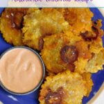 Tostones stacked on a blue plate with a small bowl of mayo-ketchup sauce.