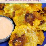 Tostones stacked on a blue plate with a small bowl of mayo-ketchup sauce.