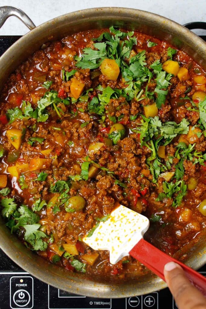 Mixing cilantro into picadillo.