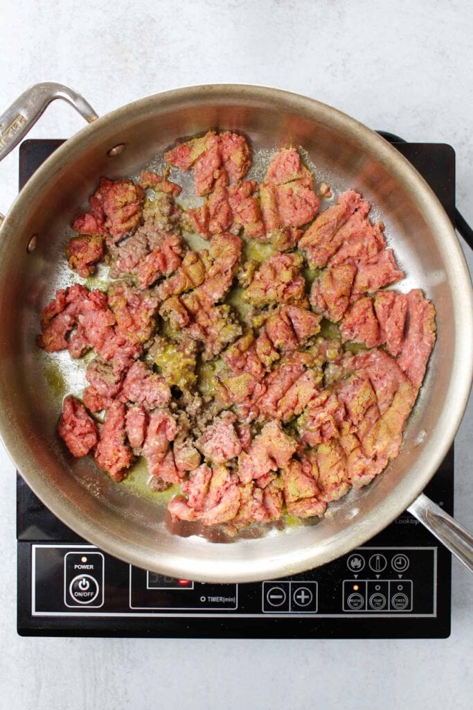 Browning ground beef seasoned with adobo all-purpose seasoning in a stainless steel pan.