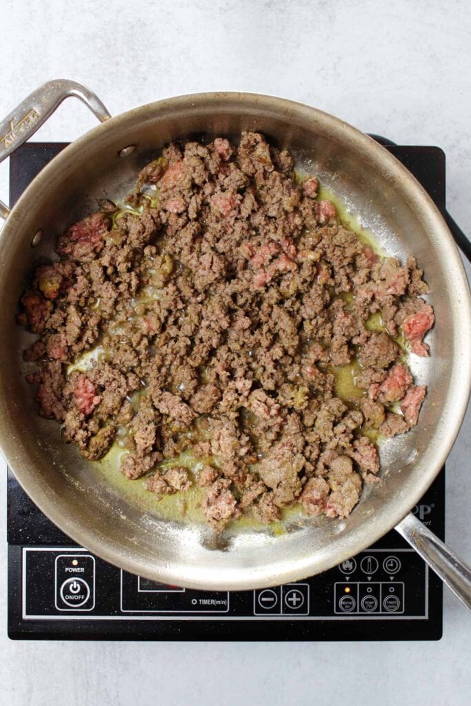 Browning ground beef seasoned with adobo all-purpose seasoning in a stainless steel pan.