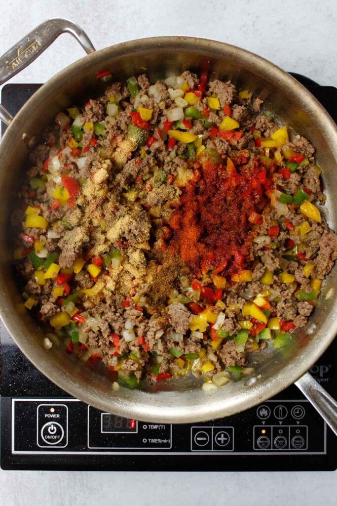 Beef, peppers, onions, sazon, and cumin in a pan.