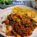 Puerto Rican picadillo plated with white rice and tostones on a pick plate, next to a large skillet filled with picadillo.