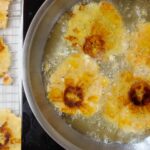 Frying pressed tostones for the second time in a large skillet.