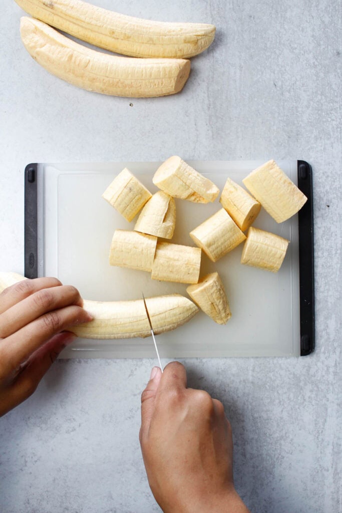 Slicing green plantains into 1-inch pieces.