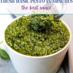 Pesto in a small white bowl being dug into with a silver spoon.