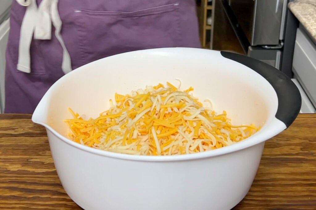 A bowl of grated muenster, sharp cheddar, mozzarella, and pepper jack cheeses.