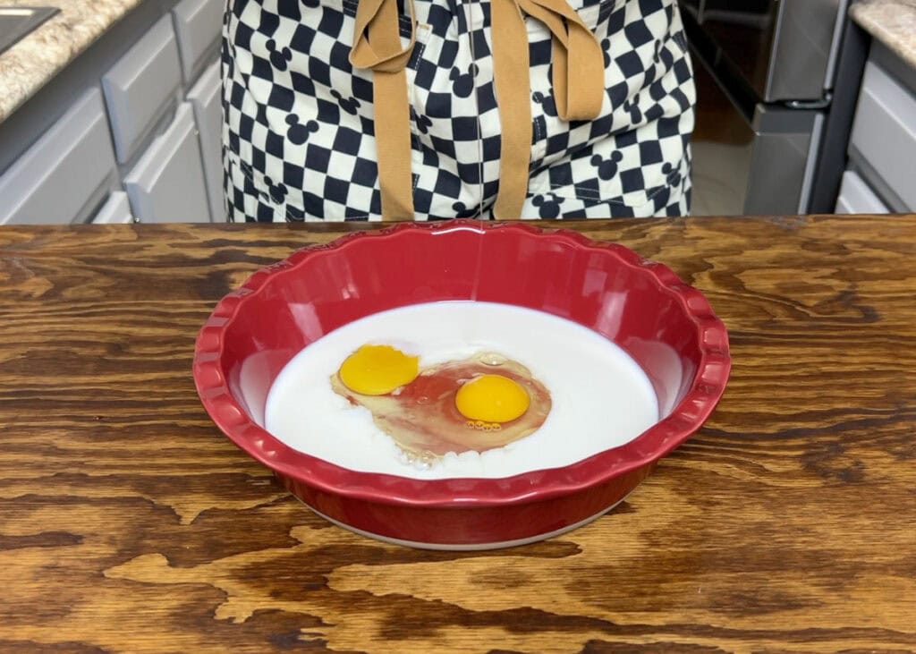 Milk and two eggs in a shallow pie dish.