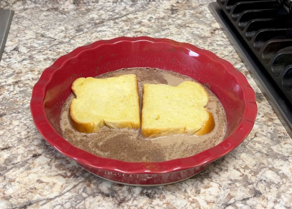 Two slices of brioche sitting in french toast custard.