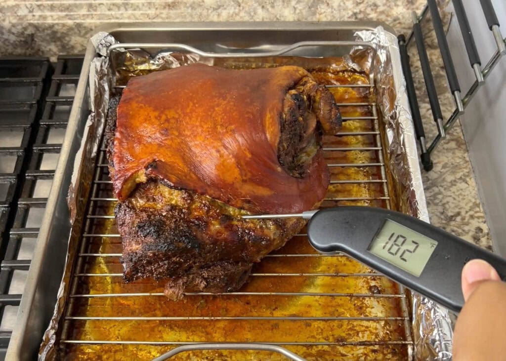 Taking the internal temperature of a whole roasted pork shoulder with a thermowork thermometer.