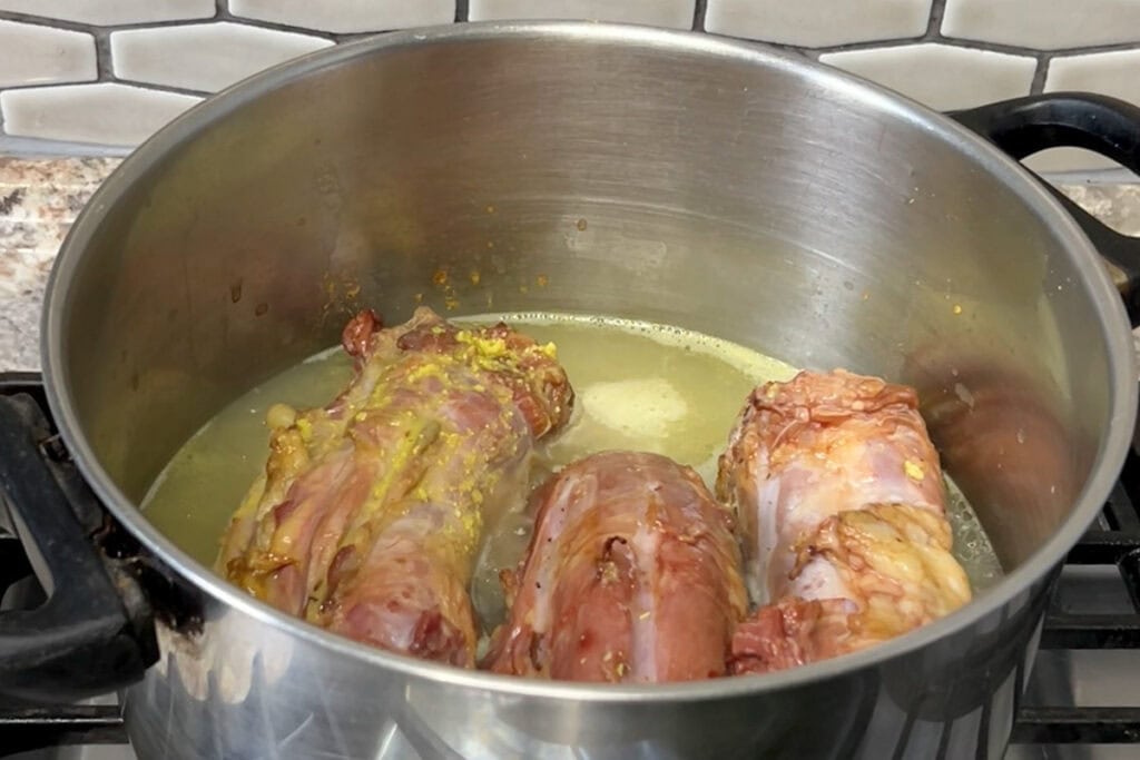 Three turkey necks in a large pot with chicken stock.