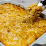 Taking a scoop out of a dish of four cheese baked macaroni and cheese.