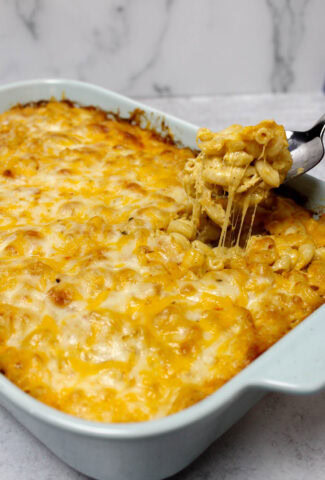 Taking a scoop out of a dish of four cheese baked macaroni and cheese.