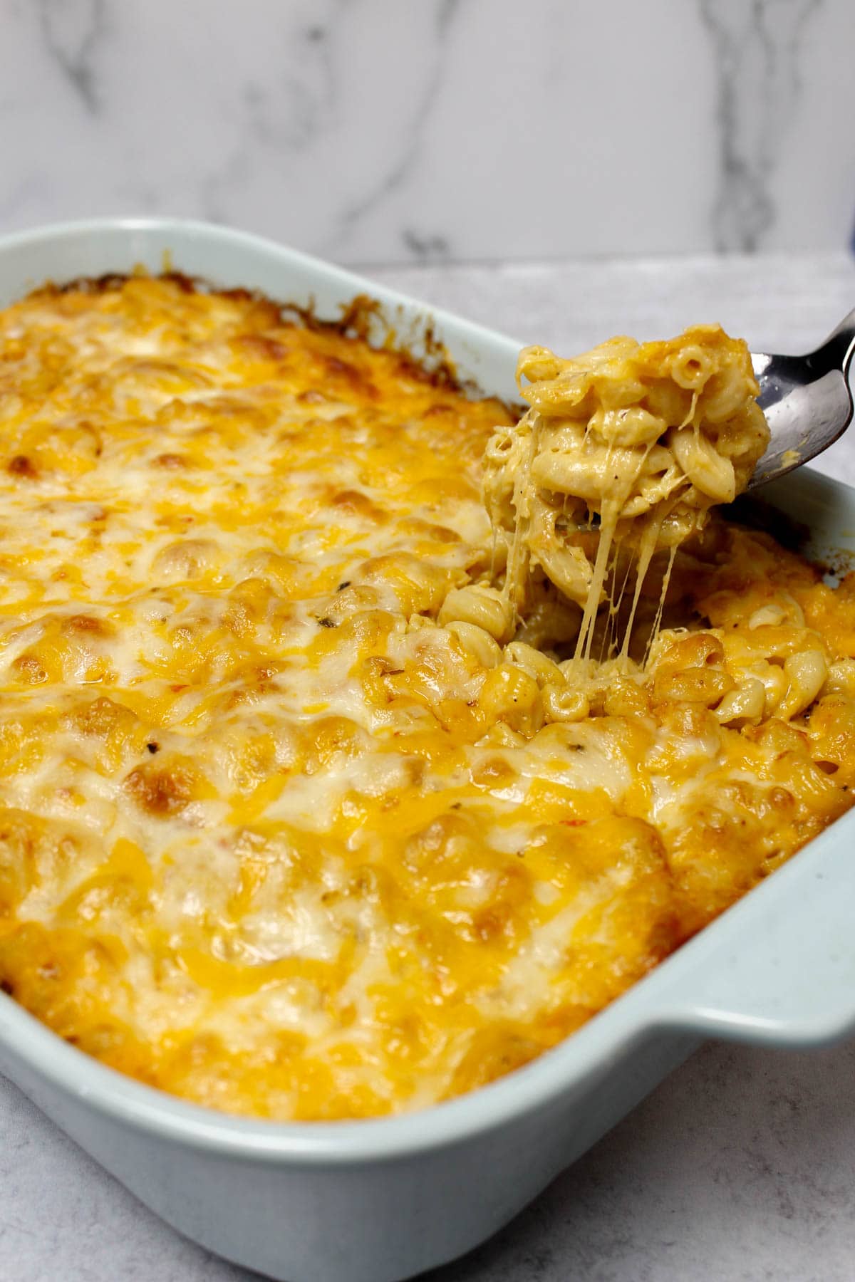 Taking a scoop out of a dish of four cheese baked macaroni and cheese.