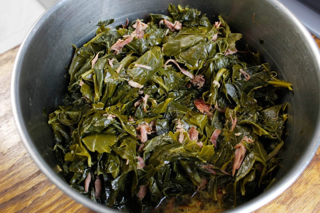 Collard greens with smoked turkey necks in a large pot.