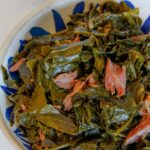 Collard greens with smoked turkey necks in a blue bowl.