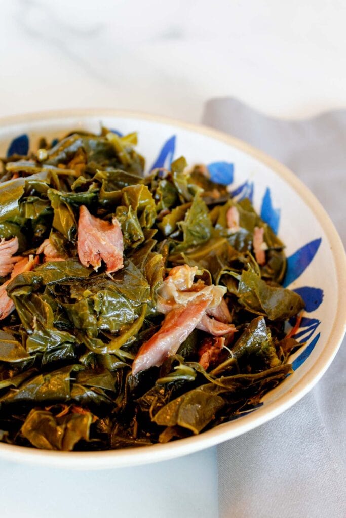 Collard greens with smoked turkey necks in a blue bowl.