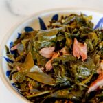 Collard greens with smoked turkey necks in a blue bowl.