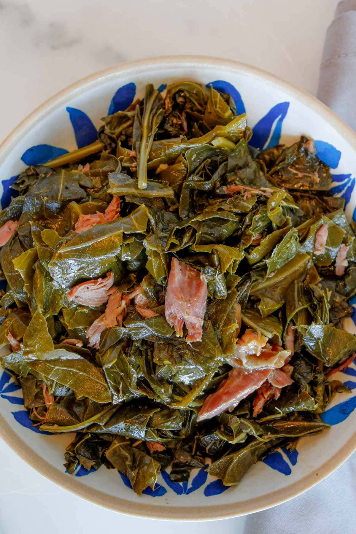 Collard greens with smoked turkey necks in a blue bowl.