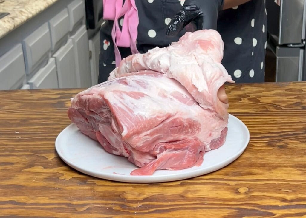 Peeling the skin back on a raw pork shoulder.