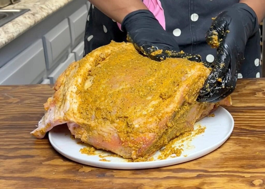 Spreading garlic marinated on raw whole pork shoulder.