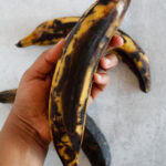 Holding a ripe yellow and black plantain.