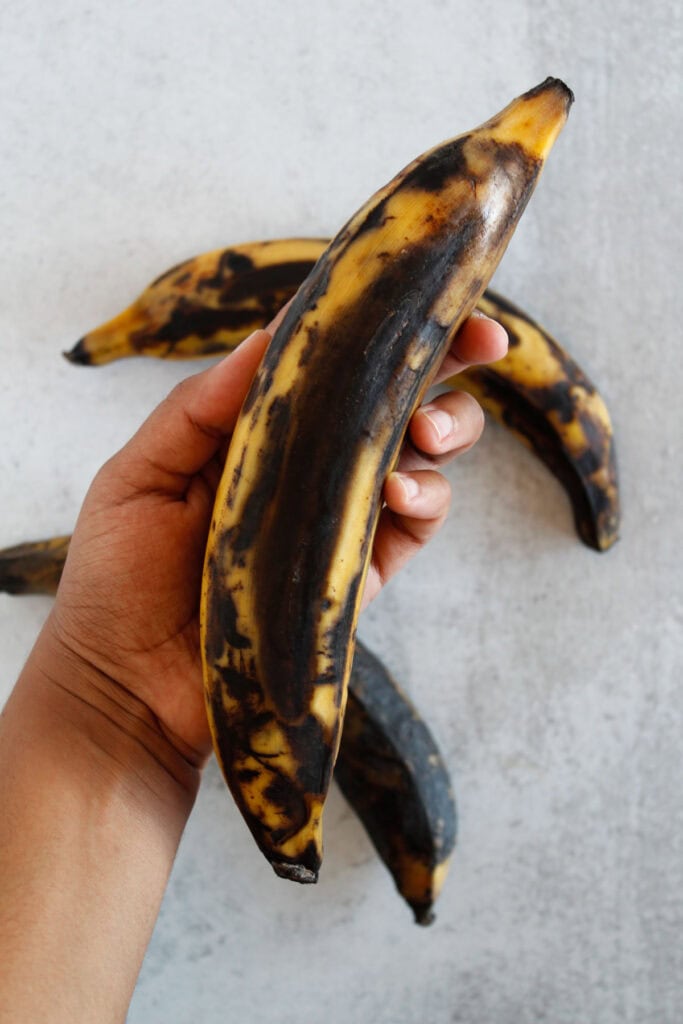 Holding a ripe yellow and black plantain.