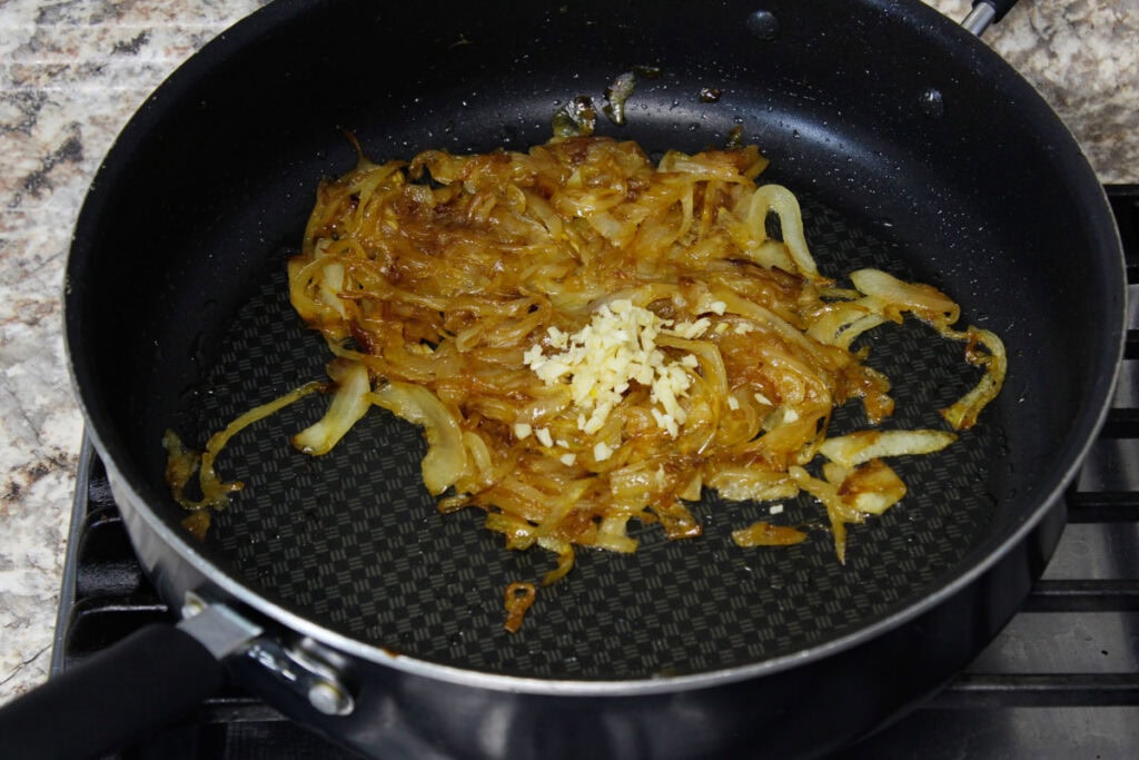 Adding minced garlic to caramelized onions.