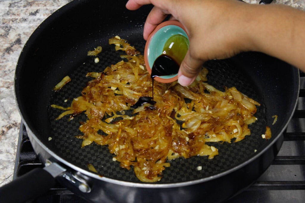 Adding aged balsamic vinegar to caramelized onions.