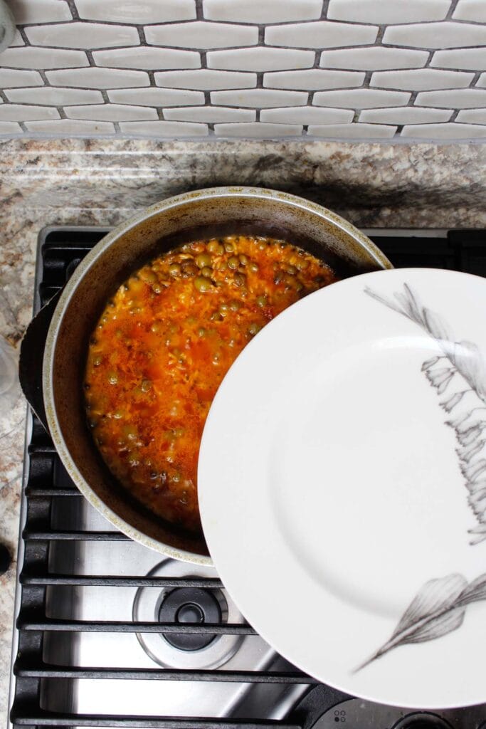 Covering arroz con gandules with a lid.