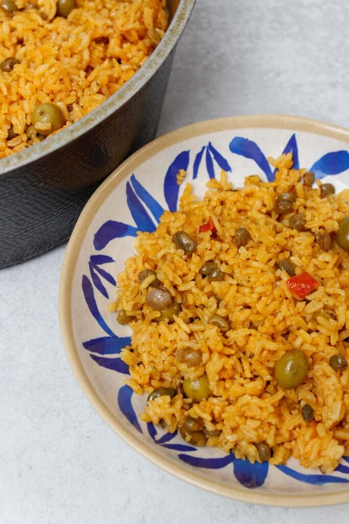 Arroz con gandules in a caldero and a blue and white plate.