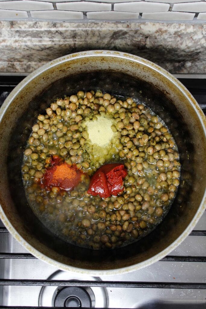 Gandules, sofrito, tomato paste, sazon, and adobo all purpose seasoning in a pot.