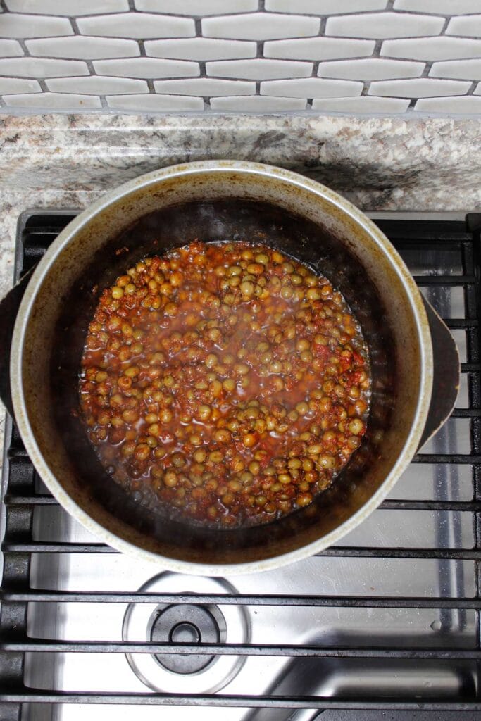 Gandules, sofrito, tomato paste, sazon, and adobo all purpose seasoning in a pot.