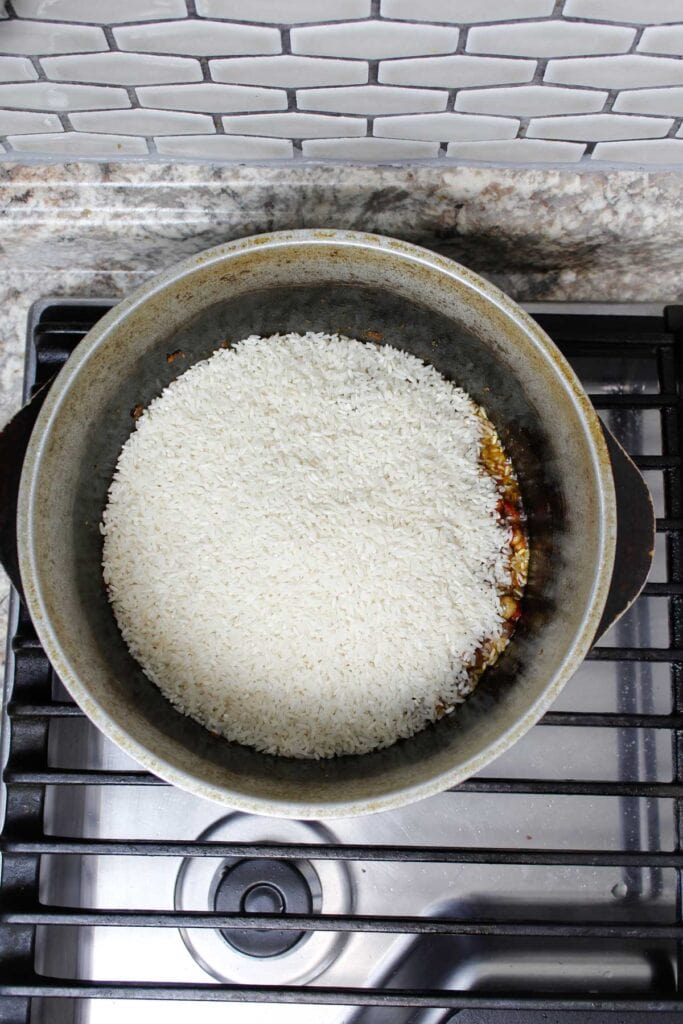 Adding rice into arroz con gandules