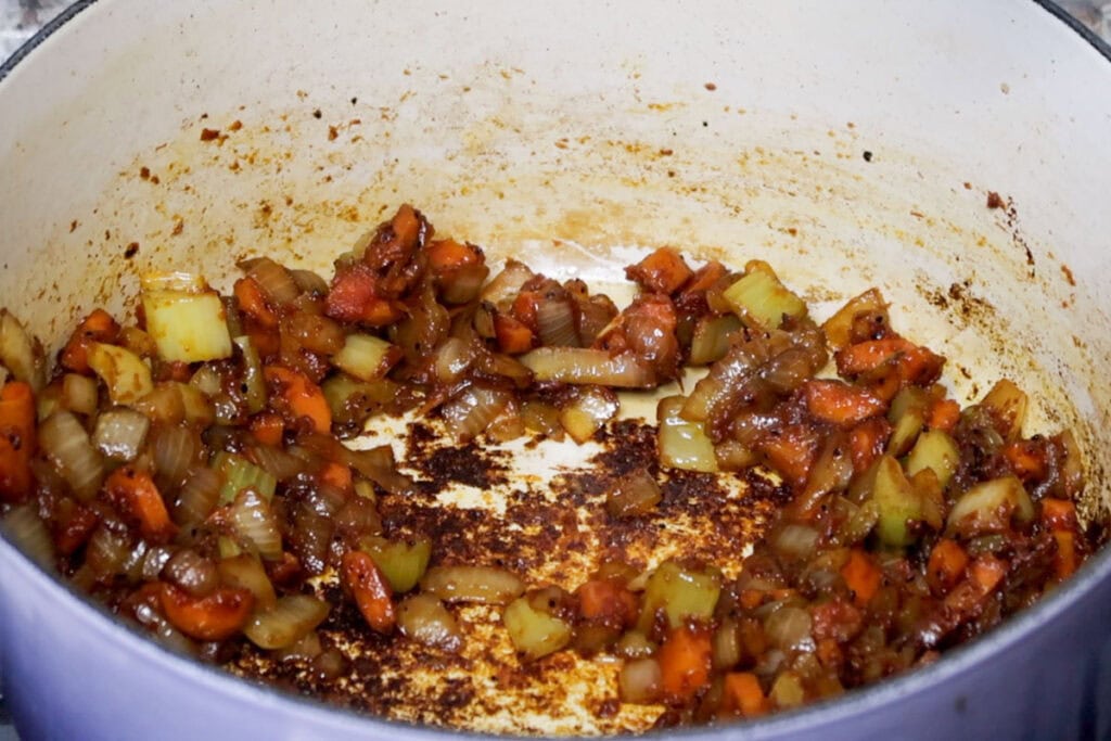 Cooking out tomato paste in mirepoix.