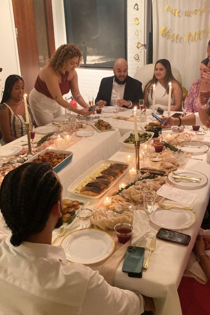 Dinner party hosted by chef Speshyl. Candle lit dinner table with food and guests surrounding.